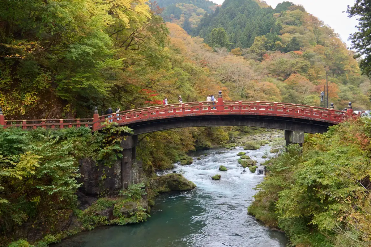 The vermilion Shinkyo Bridge over the Daiya River in Nikko with autumn trees